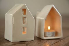 a small white house shaped candle holder with a lit candle in the front and side