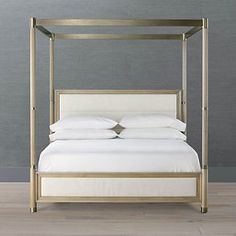 a four poster bed with white sheets and pillows on the bottom, against a gray wall