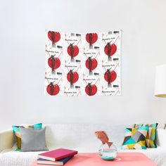 a living room with a white couch and colorful pillows on the sofa, along with a red wall hanging above it