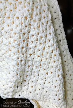 a white crocheted blanket sitting on top of a black chair