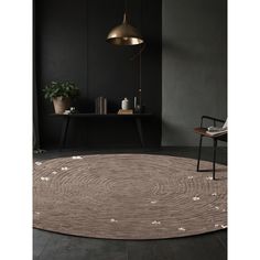 a round rug with white flowers on it in a dark room next to a chair and table