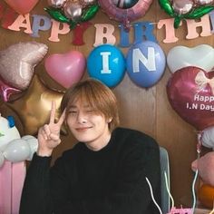 a person sitting in front of a table with balloons and decorations on the wall behind them