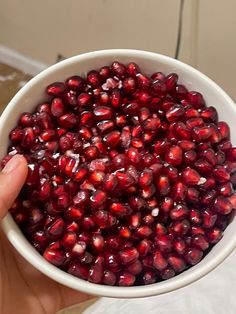 a person holding a bowl full of pomegranate