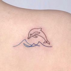 a small dolphin tattoo on the back of a woman's upper arm and shoulder