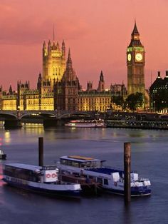 the big ben clock tower towering over the city of london at dusk with boats on the river thames