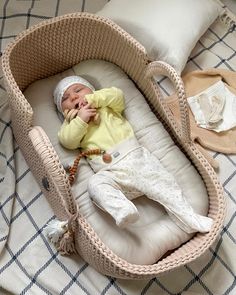 a baby is laying in a wicker bassinet