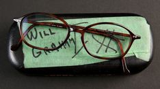 a pair of brown glasses sitting on top of a black case with writing on it