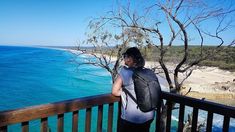 a person standing on a balcony looking out at the water and beach in the distance