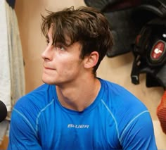 a young man sitting in front of a microphone wearing a blue shirt and looking off into the distance