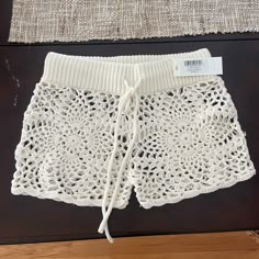 a pair of white crochet shorts with a price tag on it sitting on a table