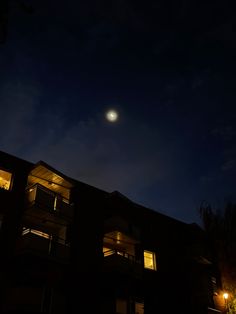 an apartment building at night with the moon in the sky