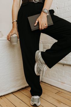 a woman is sitting on the edge of a bed with her legs crossed and holding a purse