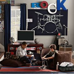 two people sitting on couches in front of a wall with musical instruments and drums