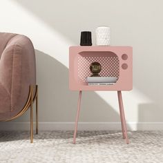 a pink side table with a magazine rack and vase on it next to a chair