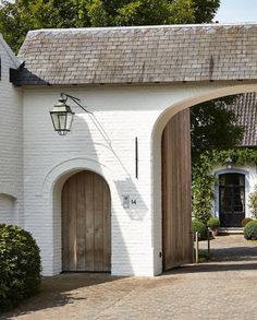 a white brick building with an arched doorway and wooden door leading into the yard area