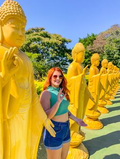 a woman standing in front of yellow statues with her hands on her hips and looking at the camera