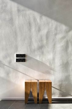 two wooden stools sitting in front of a white wall