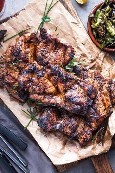 pork shoulder steaks are served on parchment paper with salad in the background and text overlay that reads pork shoulder steaks flavorful juicy tender