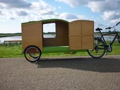 a bike is parked next to a cart with a box on the back and side