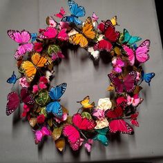 a wreath made out of colorful butterflies on a gray tablecloth with white and pink flowers