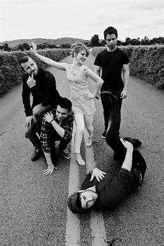 four people standing on the side of a road with their arms in the air and one person laying on the ground