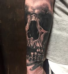 a man's arm with a black and grey skull tattoo on the left arm