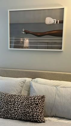 a bed with two pillows on top of it next to a wall mounted art piece