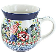 a blue and white mug with flowers painted on the side, sitting in front of a white background