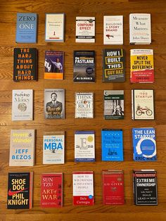 there are many books laid out on the wooden table together, all lined up in rows