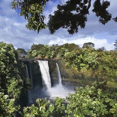 a large waterfall surrounded by lush green trees