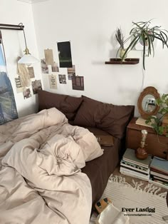 an unmade bed sitting in a bedroom next to a dresser and potted plant