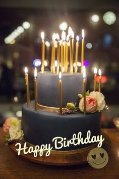 a blue cake with candles and flowers on it