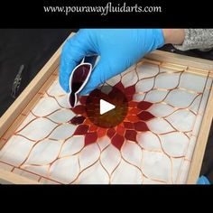 a person in blue gloves is making a glass flower