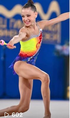 a woman in a colorful leotard holding a tennis racquet and smiling