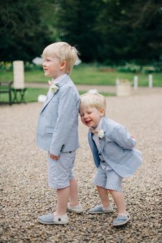 two young boys dressed in blue suits and bow ties, standing next to each other