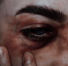 a close up of a person holding their hand to the eye of an evil looking man