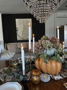 a dining room table with candles, flowers and other decorations on it's centerpiece