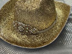 This is a gorgeous gold glitter cowboy hat adorned with a rhinestone band and gold and rhinestone center. Great for music festival or bachelorette party.  Hand decorated so no two are alike. Glitter has been sealed to help prevent shedding. Party hat. Message if you have any questions or would like to have your hat personalized. Glitter will not shed off. Gold Western Fedora Hat, Gold Fedora Western Hat, Gold Western Hat Band For Kentucky Derby, Western Gold Hat Bands For Kentucky Derby, Gold Western Hat Band For Western-themed Events, Western Gold Hat Band For Rodeo, Western Gold Hat Bands For Party, Gold Western-style Hat Band For Western-themed Events, Western Style Gold Hat Bands For Parties