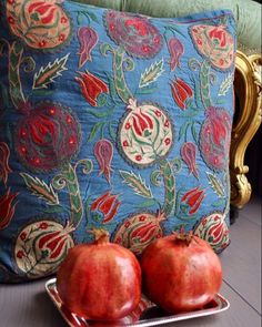 two pomegranates sit on a tray in front of a decorative pillow