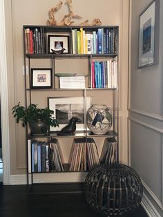 a bookshelf filled with lots of books next to a wall mounted birdcage