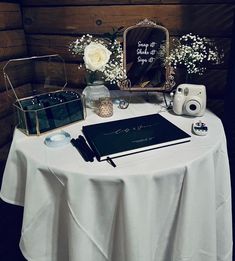 a table topped with a notebook, camera and other items next to a wooden wall