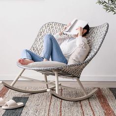 a woman is sitting in a rocking chair with a book on her head and reading