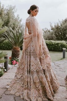 a woman standing in front of some flowers wearing a dress with an intricate pattern on it