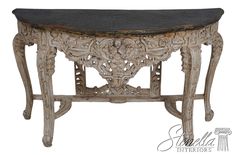 an ornately carved table with black marble top