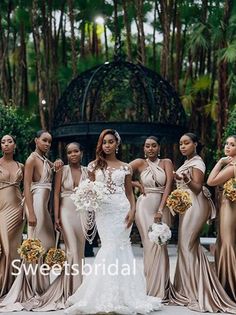 a group of women standing next to each other in front of some trees and bushes