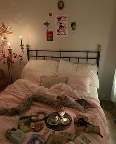 a bed that has some books on it and candles in front of the headboard