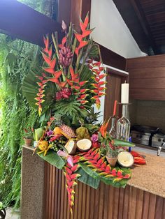 an arrangement of tropical flowers and candles on a counter