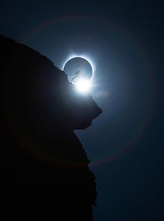 a person standing on top of a mountain under the moon