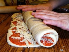 someone is making a pizza roll with cheese and tomato sauce on the top, while another person holds out their hand over it