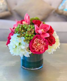 a vase filled with pink and white flowers on top of a table next to a couch